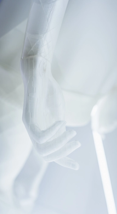 Macro close-up of a translucent mannequin arm and hand from the Blend — Frozen in Time collection, showing the semi-transparent material and internal structure. A glowing neon strip is visible in the background.