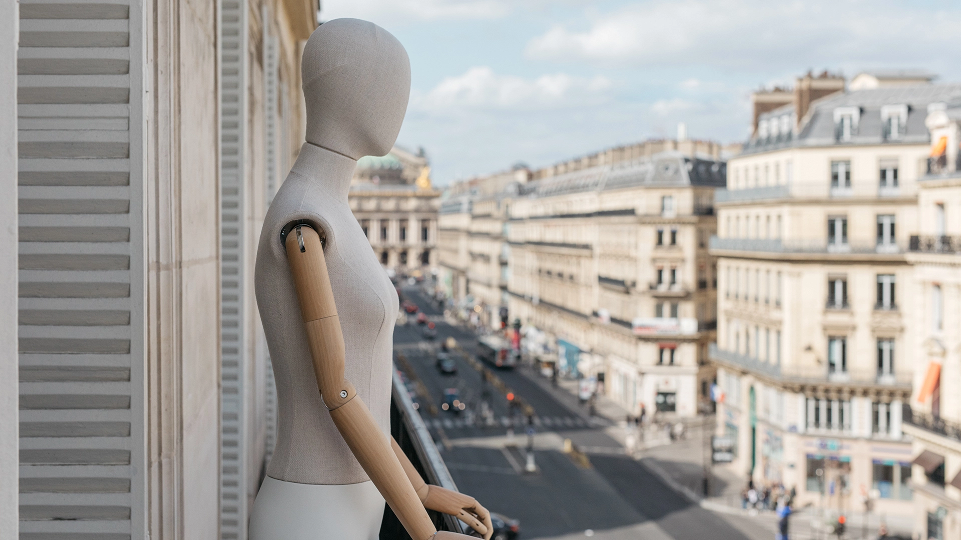 a female fabric mannequin from the essential collection looking out over Paris on a balcony