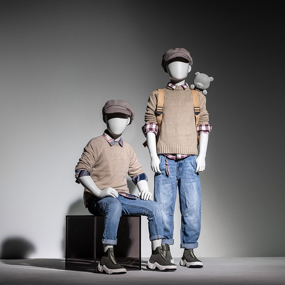 a pair of boy kids mannequins from the kids collection with a fuzzy bear next to them